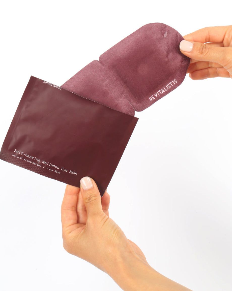 Hands opening a Revitalist15 self-heating eye mask pouch, showing how to open and the pouch and remove the mask before use.