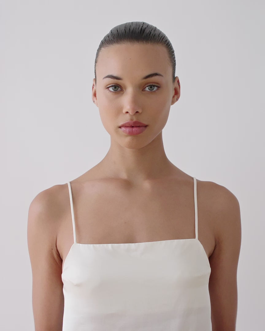 Woman placing a Revitalist15 self-heating eye mask over her eyes, demonstrating how to position and secure the ear loops.