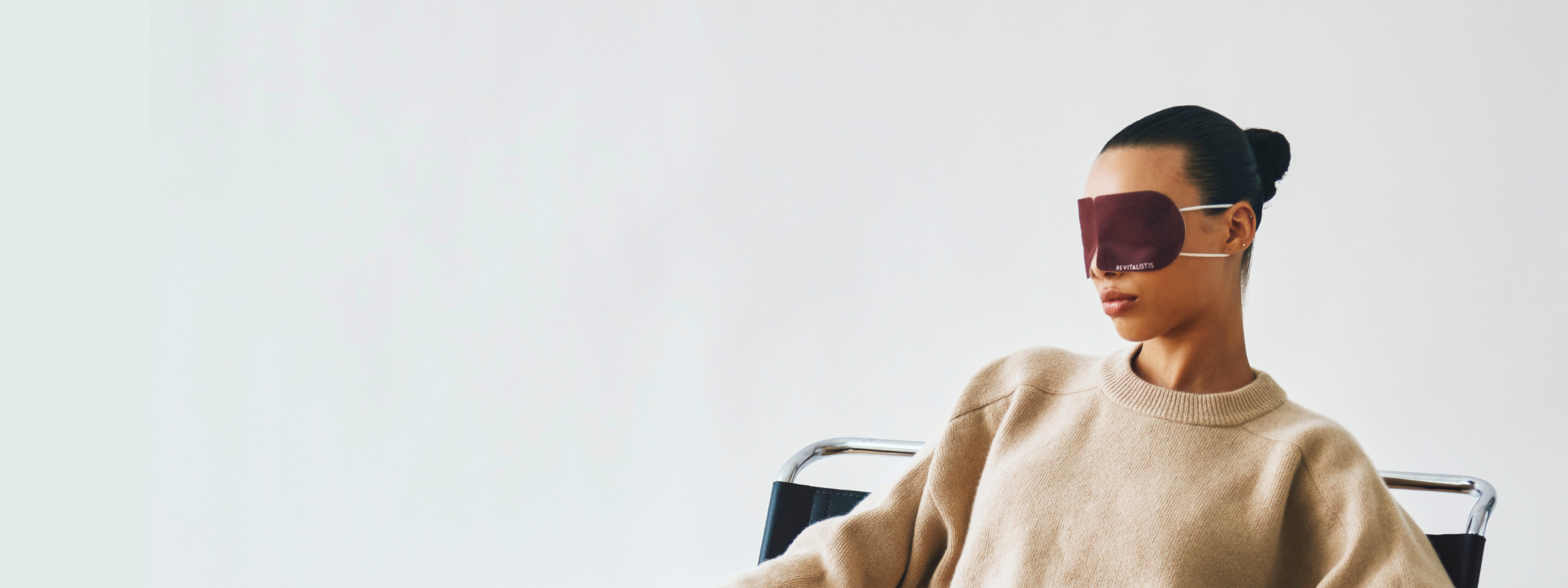 Woman wearing Revitalist15 self-heating eye mask in a minimalist setting for immediate relaxation