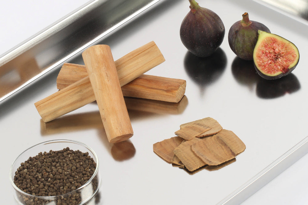Sandalwood, fig, and botanical ingredients displayed on a reflective tray, representing the natural elements in Revitalist15’s proprietary sandalwood blend.