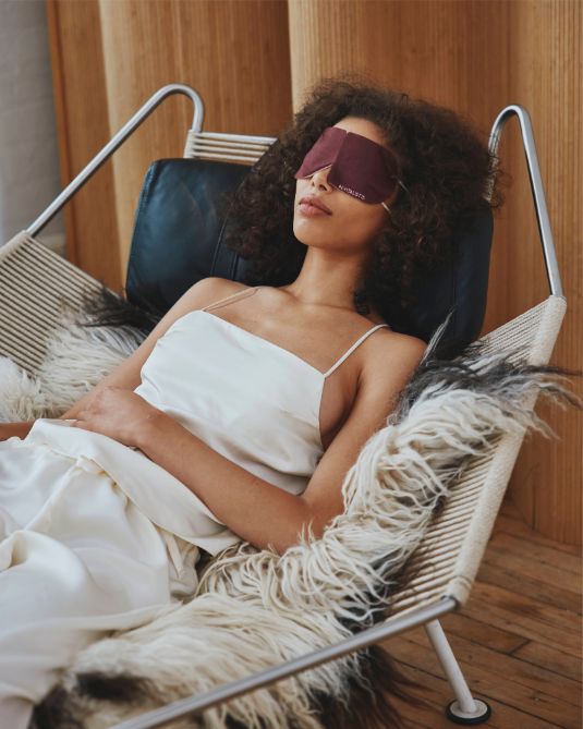 Woman reclining with a Revitalist15 self-heating eye mask, evoking calm and restoration.