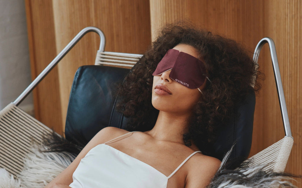 Woman reclining with a Revitalist15 self-heating eye mask, evoking calm and restoration.