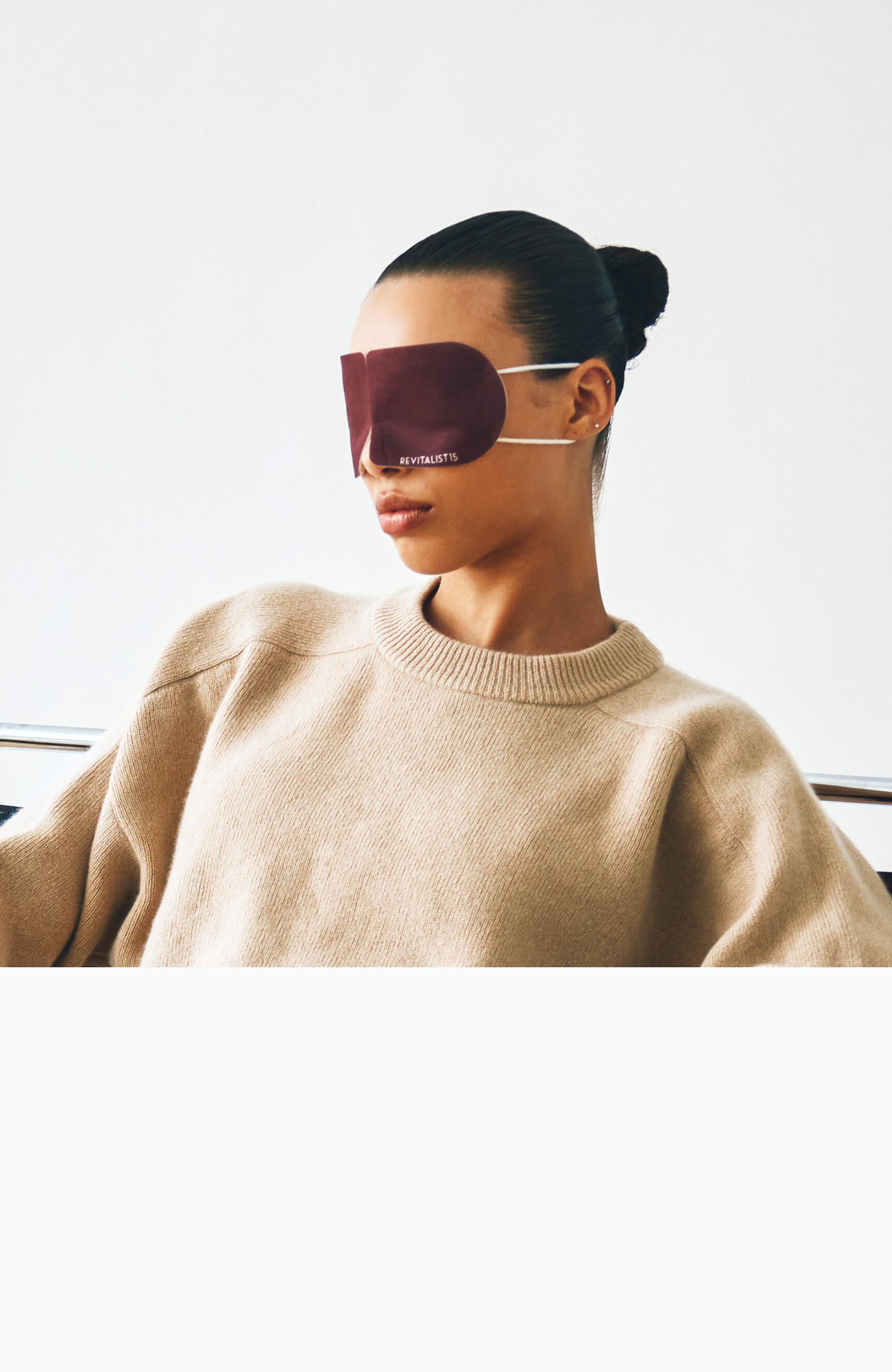 Woman wearing Revitalist15 self-heating eye mask in a minimalist setting for immediate relaxation