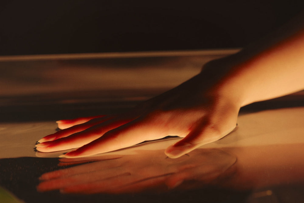Hand resting on a softly lit warm surface, symbolizing the soothing comfort and restorative benefits of heat therapy.